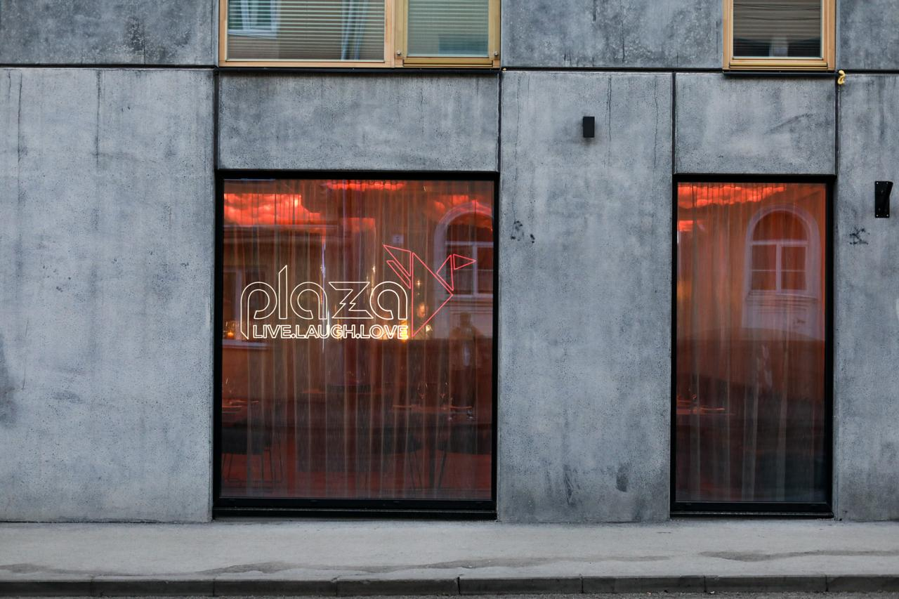 Sushi Plaza Kalamaja sissepääs Vana-Kalamaja tänaval, aknas valgustatud „plaza“ märgiga